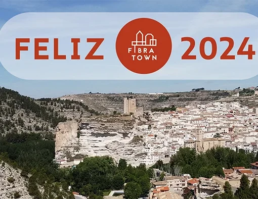 Imagen Fibratown Portada post - Feliz 2024 en la que se aprecia una panoramica de Alcala del jucar Junto a un rotulo que pones Feliz 2024 Junto al logotipo de Fibratown